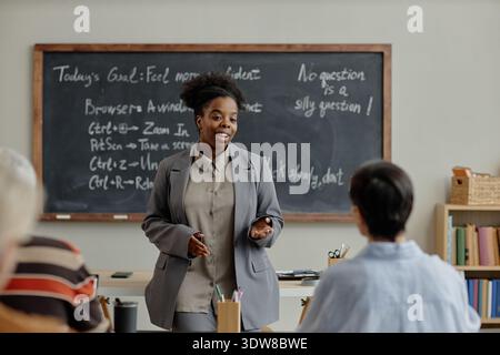 Young Adult Black Woman Teaching Classroom Lesson to Diverse Adult Students Stock Photo