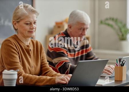 Senior Caucasian Woman and Man Using Laptops While Studying in Classroom Stock Photo