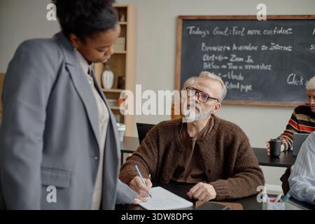 Middle Aged Caucasian Man Listening to Black Woman Teacher Explaining Lesson Stock Photo