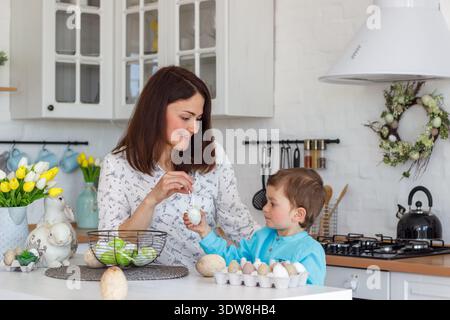 Happy Family Preparing for Easter at Home, Mom and Child Coloring Eggs, Festive Atmosphere, Spring Holiday and Parenting Lifestyle Stock Photo