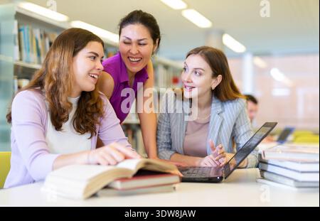 Three female friends studying together at library Stock Photo