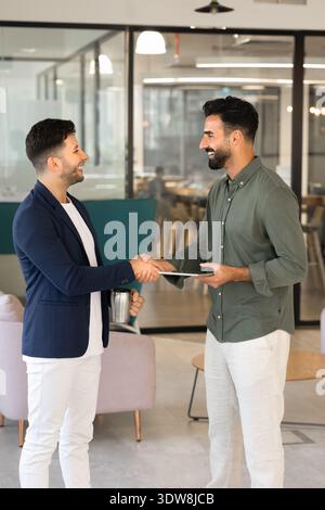 Smiling businessmen colleagues greeting with handshake in corporate office Stock Photo