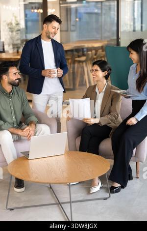 Multiethnic business colleagues collaborating, discussing project ideas in office lounge Stock Photo