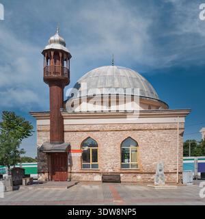 Sazibey Ak Mosque, a historic building with stone walls, wooden minaret, and large dome, in Konya Culture Park, Konya, Turkey, under a blue sky with clouds Stock Photo