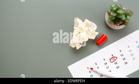 Top view of a calendar with a red circled date, a marker pen and crumpled paper on a green surface. Deadline and planning failure concept. Stock Photo