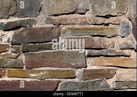 Old stone wall background.Decorative stone wall with beautiful hewn stone.Light brown stone wall in panoramic close-up made of old, roughly hewn, diff Stock Photo