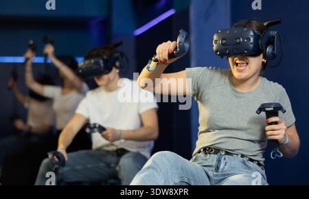 girl in virtual reality glasses controls superhero with joystick in exciting action game simulator Stock Photo