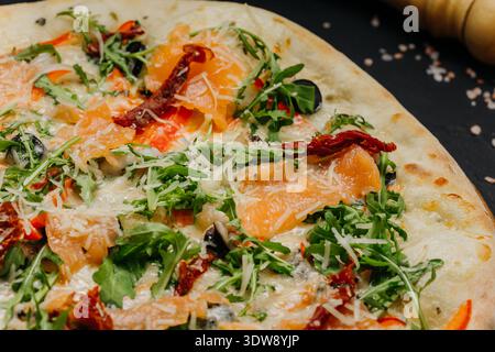 Gourmet pizza with salmon arugula cheese and sun dried tomatoes on wooden board Stock Photo