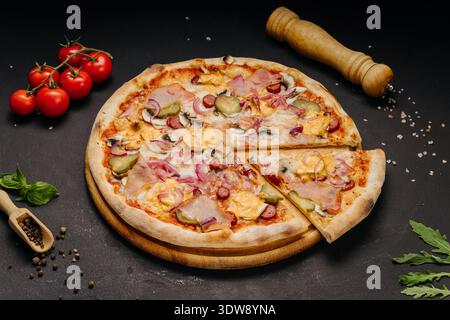 Fresh baked pizza with ham sausage cheese and vegetables on dark rustic background Stock Photo