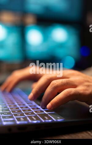 Closeup of hands typing on laptop during software programming tasks at office. Caucasian developer programs on digital device, enhancing functions and strengthening company data protection. Stock Photo