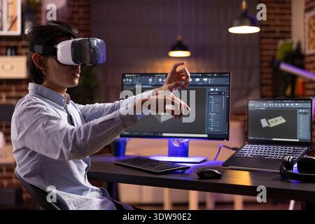 Remote worker wearing VR headset, designs mechanical prototypes using cad software. Creative developer combines virtual reality technology with computer modeling for advanced product visualization. Stock Photo