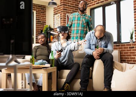 Multiethnic group reacting with frustration after female friend loses virtual reality game at home. White woman wearing VR headset shows emotional response, seated with friends in front of TV. Stock Photo
