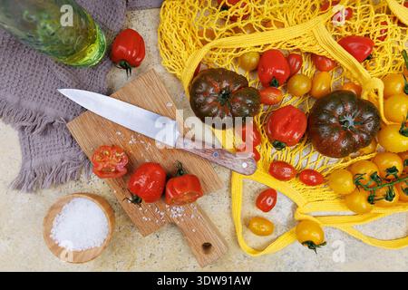 Sliced heirloom tomatoes with basil and sea salt on wooden cutting board.. Stock Photo