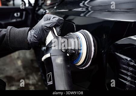 Man with orbital polisher polishing car in detailing center. Stock Photo