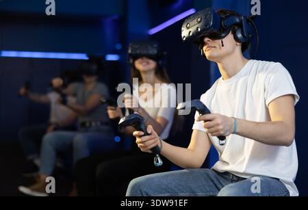 Emotional teenager in VR headset immersed in virtual reality game Stock Photo