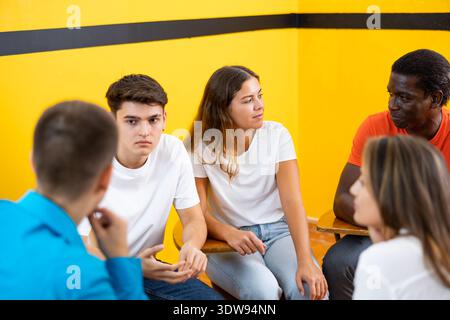 Friendly adult students chatting cheerfully while sitting in classroom Stock Photo