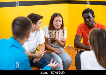 Friendly adult students chatting cheerfully while sitting in classroom Stock Photo