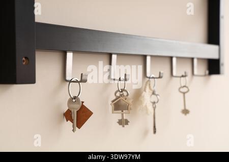 Rack with keys from house on light wall, closeup Stock Photo