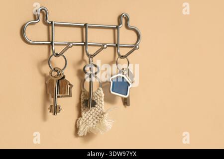 Rack with keys from house on beige wall Stock Photo