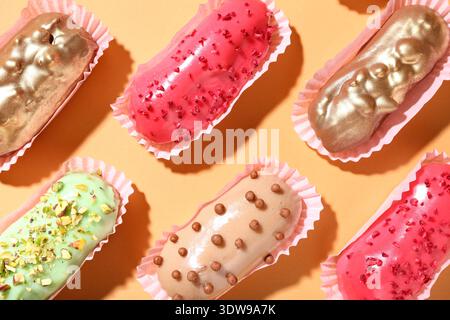 Composition with different glazed eclairs on color background Stock Photo