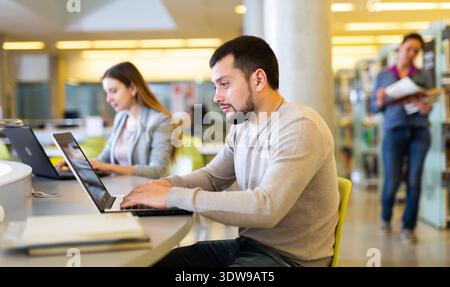 Focused man working on laptop at library Stock Photo