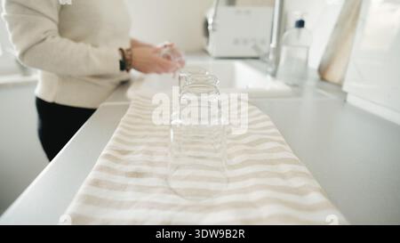 Woman Washing Glasses And Placing Them On Towel With Close-Up Of Hand Stock Photo