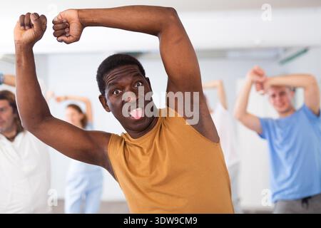Portrait of African American dancer performing dynamic dance during group training in modern fitness studio Stock Photo