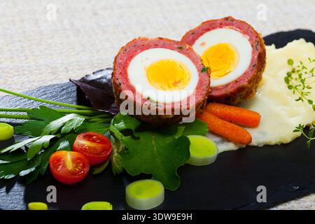 Dishes of traditional Scottish cuisine of scotch egg served with greens and potatoes Stock Photo