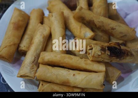 Plate of golden crispy spring rolls filled with vegetables and meat. Stock Photo
