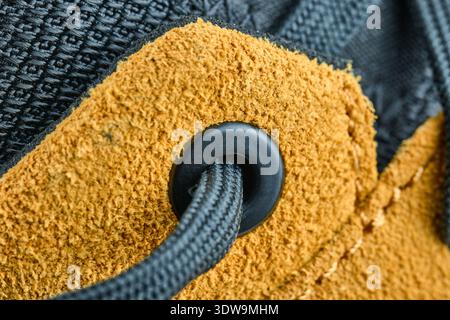 Macro shot of a black shoelace passing through a plastic eyelet on tan suede leather footwear Stock Photo