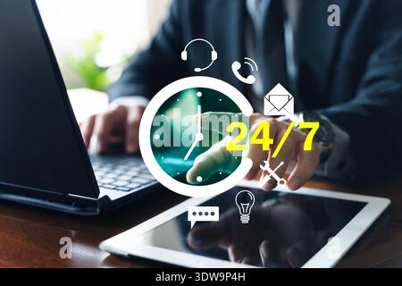 Businessman using laptop and tablet with 24/7 customer support icons. Concept of call center, help desk, technical assistance, online chat, phone and Stock Photo