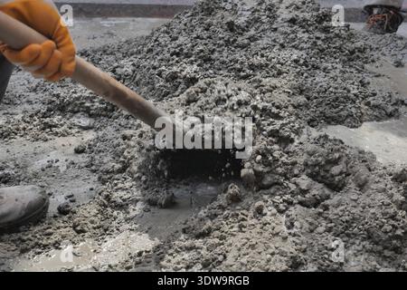 Construction worker mixes cement on a job site Stock Photo
