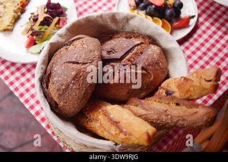 Fresh bread in a wicker basket on a checkered tablecloth Stock Photo
