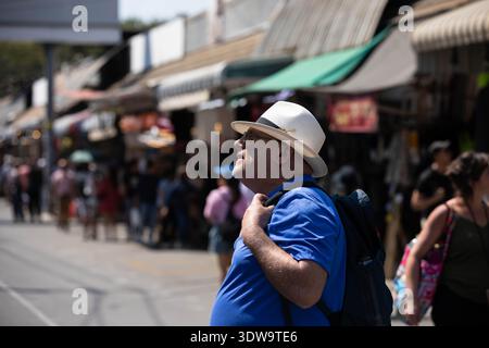 BANGKOK, THAILAND. JAN 25 2026: Senior man exploring in local market, dramatic light portrait, side view, Chatuchak Market. Stock Photo