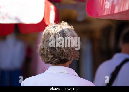 Senior woman walking in local market, alone in crowd, solitary person in busy street, hair texture, rear view, at Chatuchak Market. Stock Photo