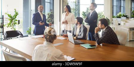Business leader speaking on office meeting in front of diverse team of employees Stock Photo