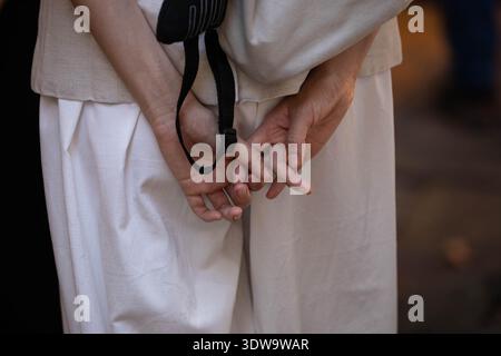 Woman's hands clasped behind back, unposed movement, natural candid motion, hand and nail skin texture, close-up, at Chatuchak Market. Stock Photo
