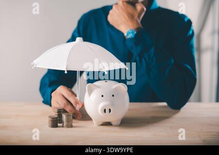 Bank piggy money protect financial insurance concept risk umbrella collage finance shown as man covers coins with white umbrella for long term investm Stock Photo