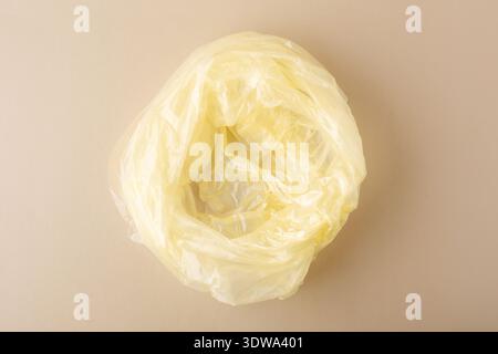 Crumpled yellow polyethylene plastic bag creating waste on a light background, symbolizing pollution and ecological concern Stock Photo