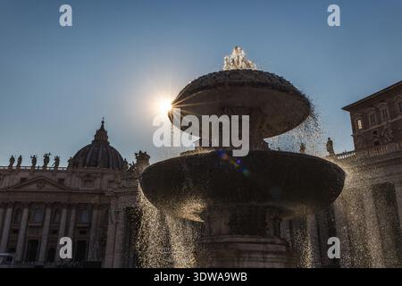Fountain in St. Peter's Square with the sun shining dramatically through water streams, Vatican City landmark at sunrise Stock Photo