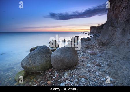 Rocky beach with large boulders on the cliffs on the Bay of Greifswald at dusk after sunset, Moenchgut nature reserve, Gross Zicker, Moenchgut peninsu Stock Photo