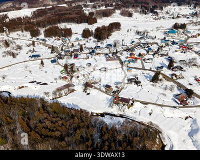 Winter landscape showing small houses with colorful roofs amidst white snowy fields Stock Photo