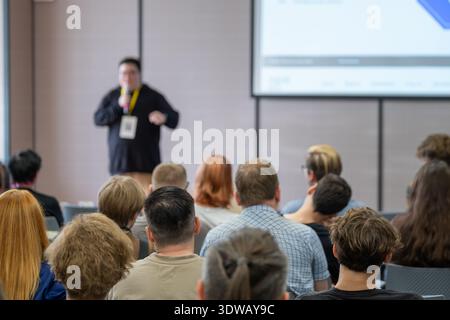 Lecturer presents to attentive audience in conference room with screen projection. Stock Photo