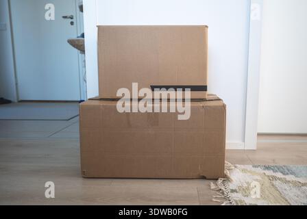 Cardboard moving boxes stacked on floor in minimalist home interior Stock Photo