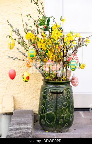 Bright spring bouquet with forsythia, willow branches and painted eggs in decorative ceramic pot. Traditional Easter decor and seasonal celebration. Stock Photo
