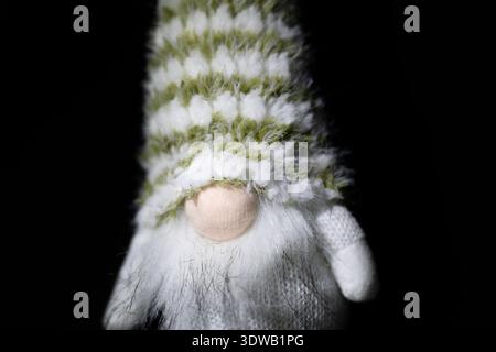 Cute gnome doll with striped knitted hat on black background Stock Photo