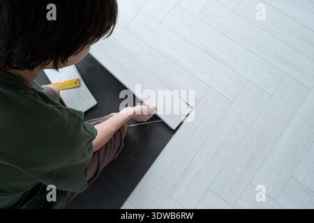 A man lays a quartz laminate on the floor. Renovation of premises. Installation of Modern flooring Stock Photo