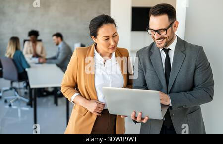 Happy multiethnic businesspeople laughing while collaborating on a new project in an office. Stock Photo