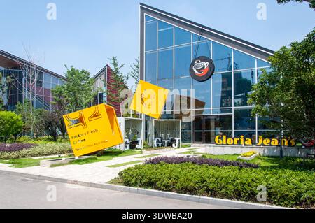 Wuhan, Hubei Province, China - June 07, 2017: The modern building exterior of a Gloria Jean's Coffee shop featuring a large glass facade and yellow ar Stock Photo