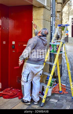 Decorator painting dark red entrance to shop - Loches, Indre-et-Loire (37), France. Stock Photo